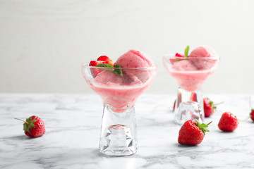 Delicious pink ice cream served with strawberries in dessert bowls on marble table