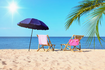 Empty wooden sunbeds and beach accessories on sandy shore