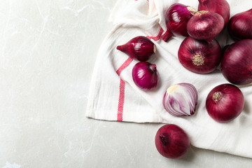 Napkin with fresh red onion bulbs and space for text on white marble table, flat lay