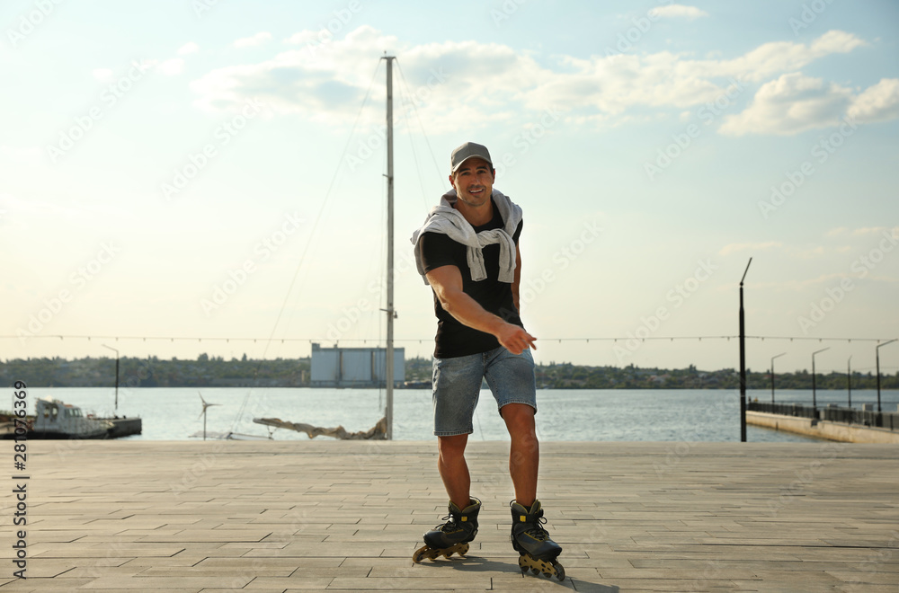 Canvas Prints Handsome young man roller skating on pier near river