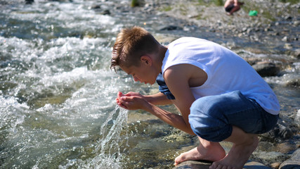 Fototapeta premium The guy washes himself cold mountain water.Early morning traveller.