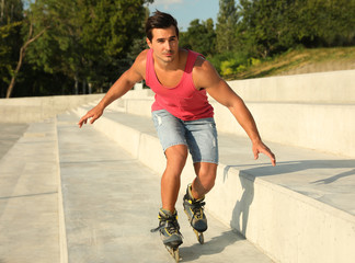 Handsome young man roller skating on city street