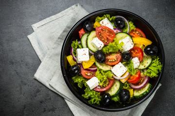 Greek salad in black plate on the table.