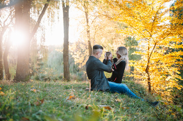 Beautiful young couple resting in autumn park. autumn concept. Loving couple resting with their cat.