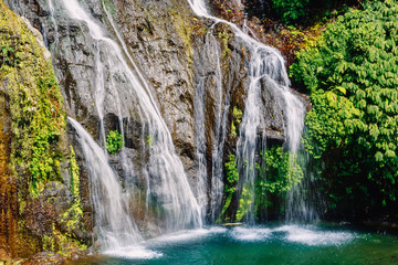 Waterfall with crystal blue water and rainbow in tropics