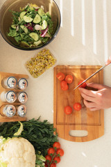 A young man prepares a very healthy salad of fresh organic vegetables and herbs. He leads a healthy lifestyle.