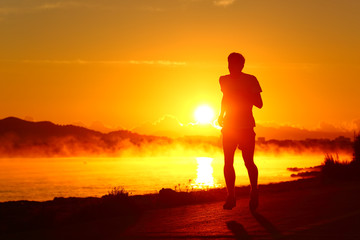 Runner silhouette running at sunset on the beach