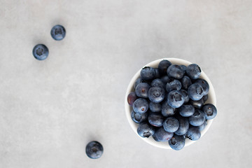 Fresh blueberries in a white bowl on a gray background. Top view.
