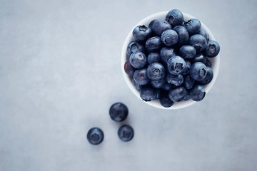 Fresh blueberries in a white bowl on a gray background. Top view.