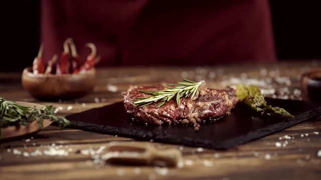 falling rosemary on delicious meat steak on table with ingredients