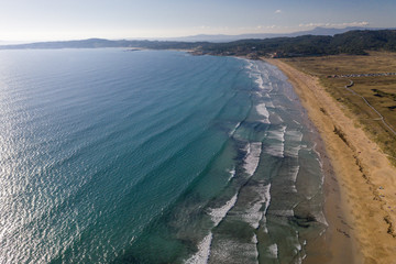 ocean waves, sandy beach with people bathing in the water, view from drone, Lanzada beach, Galicia, Spain