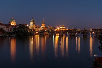 Fototapeta na wymiar Pananorma view over the river Vltava. Old Town Prague at night with the historic stone bridge. Charles Bridge with illuminated Old Town tower and reflections in the water