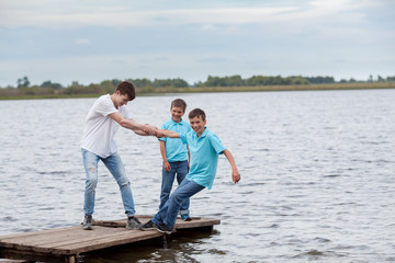 Fototapeta na wymiar Group of happy cheerful beautiful children play near lake, outdoor