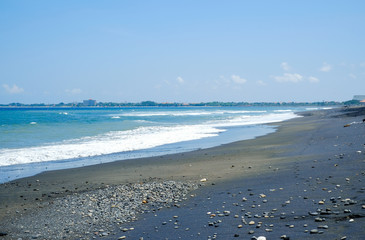Ocean coast with black volcanic sand on the island of Bali, Indonesia.