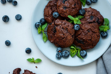 Chocolate cookies with chocolate chips and blueberry on gray wooden background. Summer food. Soft focus. Top view.