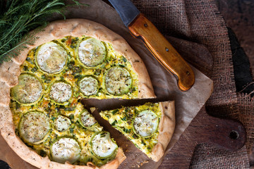 Homemade courgette and goat cheese pie on a dark rustic wooden board background