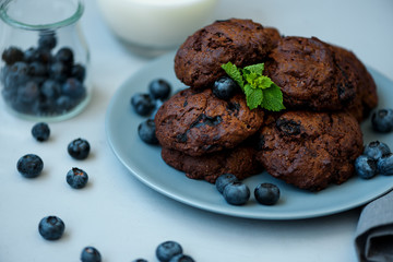 Chocolate cookies with chocolate chips and blueberry on gray wooden background. Summer food. Soft focus.