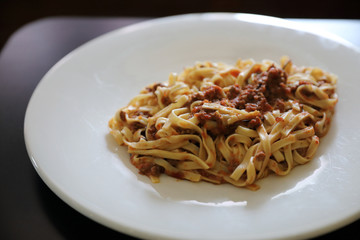 spaghetti Bolognese with minced beef and tomato sauce garnished with parmesan cheese and basil , Italian food