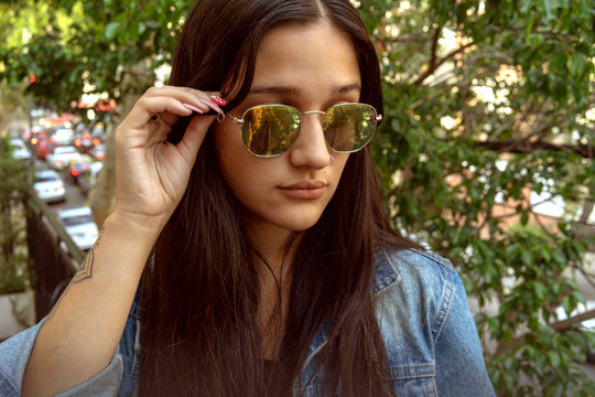 Young girl, playing to be a model in the city, in different options with her sunglasses