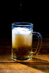Caneca de cervaja sobre a mesa de madeira natural e fundo preto