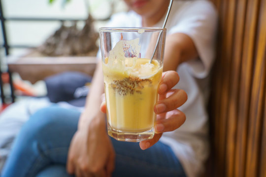 Woman holding a Vietnamese egg coffee hot and cool in the white coffee mug, cup in HANOI VIETNAM
