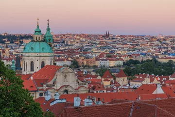 Selbstklebende Fototapeten View over Prague from the district Lesser Town with stairs from the Prague Castle with alley, historical buildings and trees in the evening. View over rooftops of Pragues Old Town with churches © Marco
