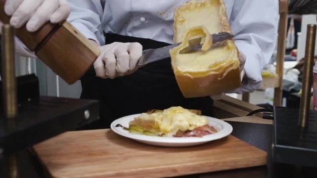 Street food vendor prepare raclette - Swiss dish, also very popular in Savoie (France), based on   heating the cheese and scraping off the melted part. 