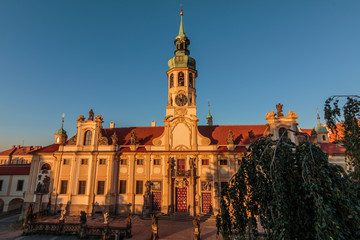 Direct view of the historic Baroque building complex in the Czech capital of in the evening sun with blue sky. Capuchin Church Loreta from Hradcany Square near the Prague Castle