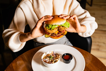 .Young woman eating burger in restaurant