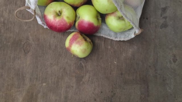 Zero waste shopping concept. Fresh organic apples in reusable recycled produce bag on wooden table. Top view.