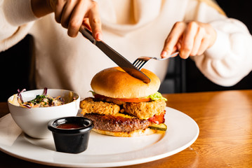 .Young woman eating burger in restaurant