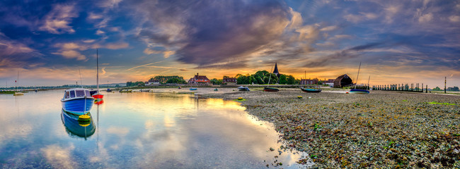 Bosham, UK - June 2, 2019:  Summer sunrise over the village of Bosham at low tide with the harbour and wadeway, West Sussex, UK