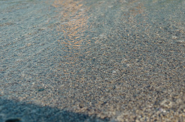 Closeup of sandy beach with soft incoming waves. Selective focus