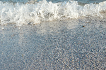 Closeup of sandy beach with soft incoming waves. Selective focus