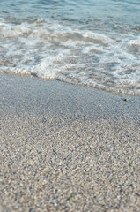 Closeup of sandy beach with soft incoming waves. Selective focus