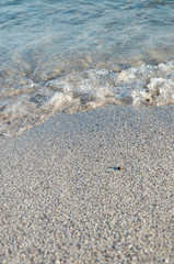 Closeup of sandy beach with soft incoming waves. Selective focus