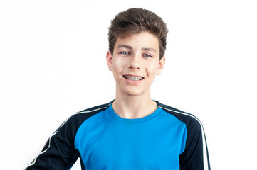 Fototapeta premium Beautiful young boy smiles genuinely on a white background. Braces are installed on the teeth of the boy