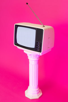 Old analog TV displaying noise against bright pink background. Vaporwave.