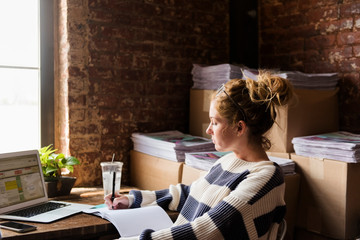 Woman writing in notebook at desk