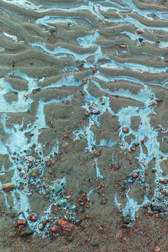 Colored water on stones and sand.Environmental pollution