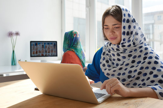 Beautiful woman with colleague using laptop in fashion studio