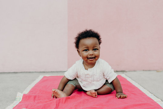 Smiling baby sitting on pink blanket