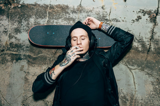 Young man smoking on rooftop with skateboard