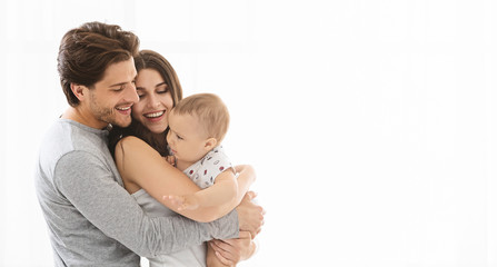 Adorable millennial family embracing at home, empty space