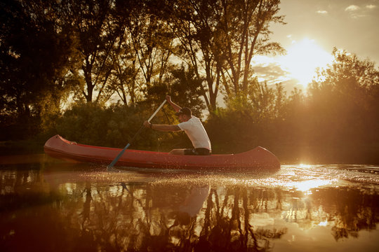 Man paddling red canoe in the river.