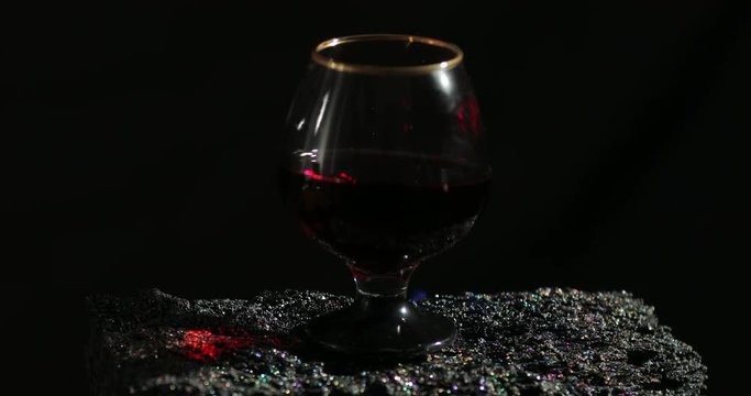 A glass of red wine on fire stands on a beautiful natural stone