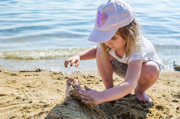 Girl plays with sand by the lake of the sea