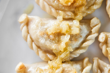 Fried dumplings stuffed with meat carmelized onion on white plate