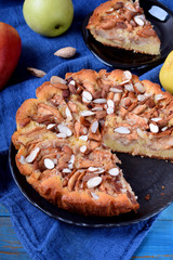 Pie with pears, apples and almonds on a black plate