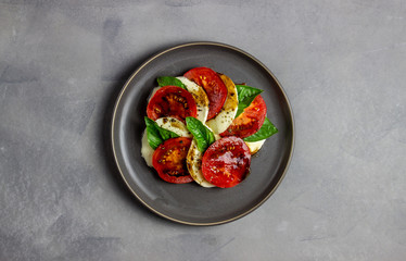 Italian caprese salad with mozzarella and tomatoes. Concrete background. Healthy food.